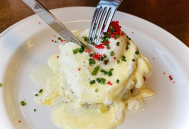 Havyar ve otlarla süslenmiş beyaz bir tabakta tütsülenmiş somon balıklı Benedict yumurtası. Hafif kahvaltı.