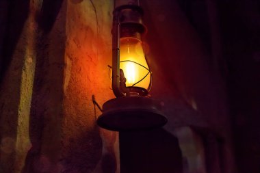 lamp in the form of an old lamp on kerosin, hanging on an old, stone wall in a room. Beautiful romance background with copy space