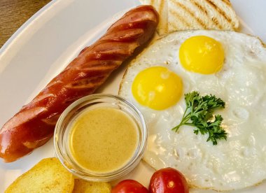 Lezzetli kahvaltı, sosisli sahanda yumurta ve tabakta tatlı hardal. Düz yatış tarzı. Üst görünüm