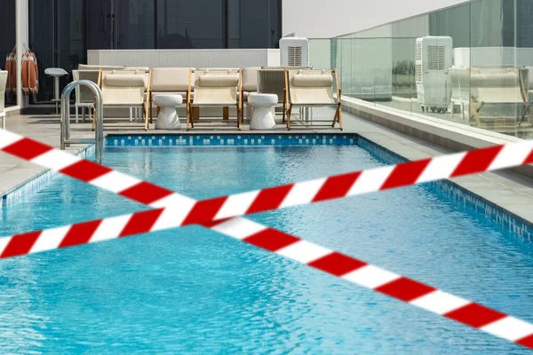 Barrier tape - quarantine, isolation, entry ban. Do not go over. empty deck chair by the clean pool