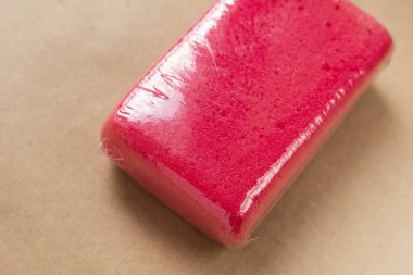 Kahverengi arka planda bir arabayı temizlemek ve yıkamak için yeni bir kırmızı mikro sünger. Boşluğu kopyala