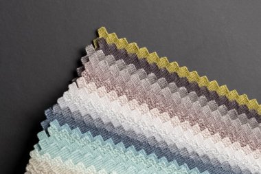 Siyah masanın üzerinde kumaş parçası koleksiyonu. Kataloğun ayrıntıları yakın plan. Arkaplan, doku