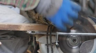 Adamın elleri eldivenli kütüğü çalışan testereye doğru hareket ettir..