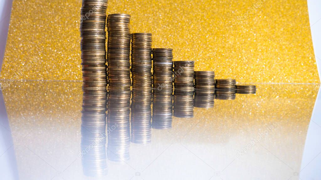 Stacks of coins with Decreasing of Interest Rates on gold background. 