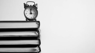 Kitapların üstünde siyah beyaz fotoğraf saati.