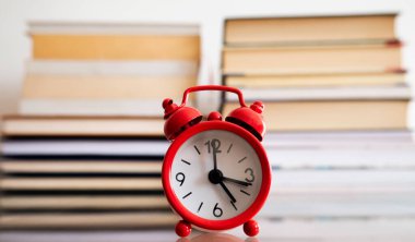 Ders çalışma zamanı. Kitapların önündeki çalar saat.