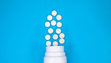 İlaç hapları ya da haplar ve mavi arka planda bir şişe. Metin için alanı kopyala.