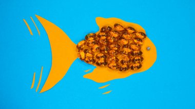Omega 3 kapsülleri, balık şekilli, mavi arka planda izole edilmiş. Üst Manzara. Sağlık hizmeti kavramı.