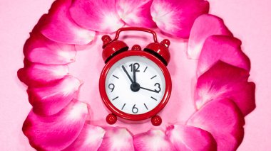 Gül yapraklarından oluşan bir çemberde kırmızı saat..