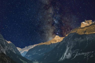 Samanyolu ve yıldızlar gece gökyüzünde bir dağda.