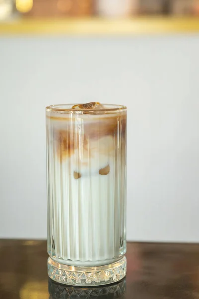 Soğuk latte. Masada kahve ve süt olan cam bardakta bir içki. 