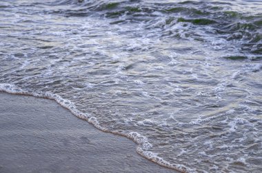 Kumsalda beyaz köpüklü yumuşak deniz dalgaları. Sahil suyu dokusu.