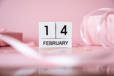 14 Şubat tahta takvim bloklarının en üst görüntüsü pembe arka planda hediye kutuları ve kurdelelerle. Sevgililer Günü düz konsept.