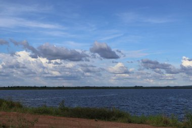 Göl ve bulutlu mavi gökyüzü ile güzel bir manzara.