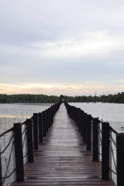 Gün batımında gökyüzü arka planıyla gölün üzerinde köprü