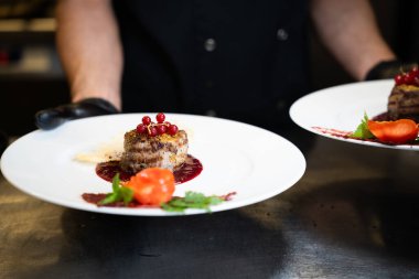 Beyaz tabakta kırmızı üzümlü gurme et madalyonu.