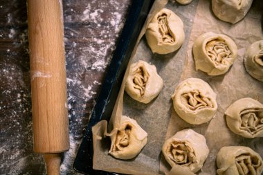 Fırın tepsisinde çiğ tarçınlı rulo. Pişirme işlemi için hazır.