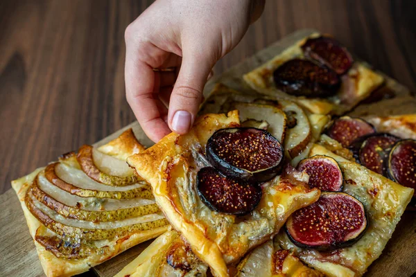 İncir ve ahşap bir tahtanın üzerinde dilimlenmiş armutla kaplı ev yapımı puf börekleri. Sıcak ve sıcak bir atmosferde altın kabuklar ve sulu meyveler. Pişirme, tatlı ya da sonbahar yemeği kavramları için mükemmel..