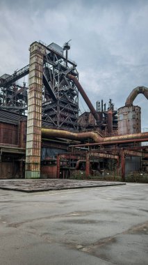 Metal boruları, bacaları ve yapıları olan güçlü bir sanayi bölgesi. Kompozisyonda eski fabrika alanının geometrisi, çürümesi ve dayanıklılığı vurgulanıyor. Endüstriyel mimari ve şehir araştırmaları için ideal.