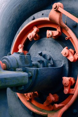 Turuncu ve mavi tonlarda boyanmış endüstriyel ekipman sisteminin yakın çekim görüntüsü. Fotoğraf civata, doku ve yaşlanma belirtilerini yakalar, makine mühendisliği, endüstriyel tasarım veya fabrika makineleri için idealdir..