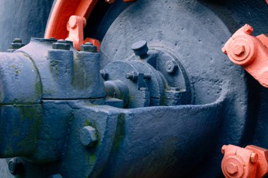 Birkaç cıvata ve kaba metal dokusuyla mavi boyalı endüstriyel makine bileşenini gösteren bir makro çekim. Görüntü, sanayi, teknoloji veya mühendislik konuları için mükemmel bir güç ve hassasiyet taşır..