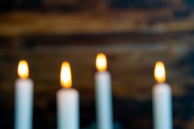 Dört sıcak alev yumuşak bir ahşap zemin üzerinde bulanık görünüyor, rüya gibi, atmosferik bir hava yaratıyor. Nazik parıltı ve altın renkler görüntüye tatil arkaplanı için uygun mevsimsel bir his verir.