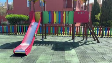 Açık alanda renkli çitleri olan çocuklar kırmızı kaydırak kullanıyor.. 