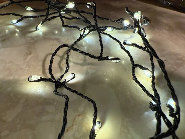 Warm white fairy lights lying on wooden surface, cozy holiday decor. 