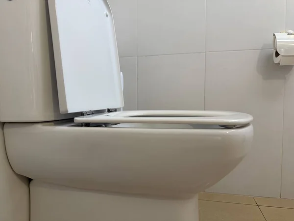 a clean white toilet with an open lid in a modern bathroom concept of hygiene and home