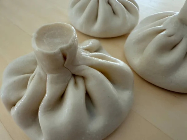 uncooked georgian khinkali dumplings on a light wooden surface food preparation concept