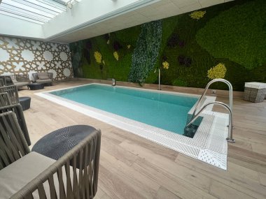 Modern dekor ve oturma düzeniyle kapalı yüzme havuzu, kopyalanmış uzay konsept spa oteli.