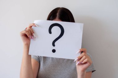 Bir kişinin elinde bir soru işareti var. Yüzü, belirsizlik ve soruşturma kavramını kapsıyor.