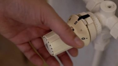 Sıcaklığı ayarlamak için termostat kullanan bir adamın eli.