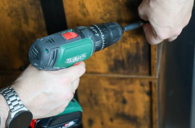 Ahşap yapıyı güçlendirmek için tornavida delen bir adamın yakın çekimi..