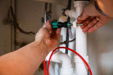 Ters osmoz sisteminin drenaj borusunu tornavida kullanarak boruyu batırmak. Yüksek kalite fotoğraf