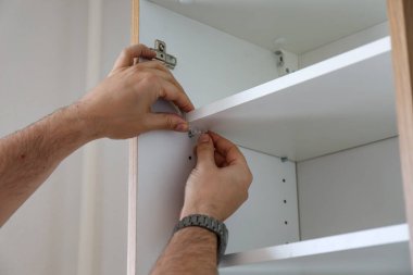 Beyaz erkek eller mobilya dolabının montajı ve kurulumu sürecinde. Yüksek kalite fotoğraf