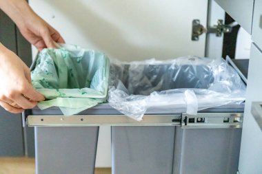 Bir ev hanımı çöp torbasıyla mutfakta çöp tenekesine yem atıyor. Atık ayırma kavramı. Yüksek kalite fotoğraf