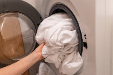 Çamaşır odasındaki çamaşır makinesine çarşaf koyan kadın elleri. Yüksek kalite fotoğraf