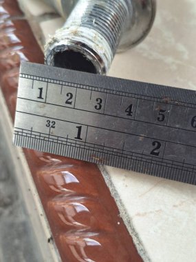 Bir atölyede çelik cetvel kullanarak metal bir borunun çapını ölçmek. Hassas ölçümlere, metalik dokulara ve endüstriyel detaylara odaklan. Mühendislik, inşaat, doğruluk, bakım ve teknik çalışma kavramı