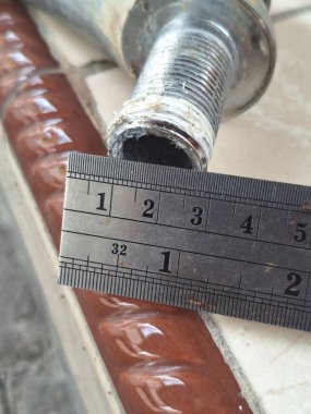 Bir atölyede çelik cetvel kullanarak metal bir borunun çapını ölçmek. Hassas ölçümlere, metalik dokulara ve endüstriyel detaylara odaklan. Mühendislik, inşaat, doğruluk, bakım ve teknik çalışma kavramı