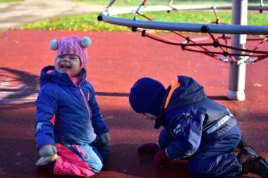 Renkli tulumlu iki çocuk soğuk bir sonbahar sabahı oyun sahasında gülüp oynuyorlar. Neşeli çocukluk arkadaşlığı anı. Kardeşler dışarıda eğleniyor, doğayı keşfediyorlar.