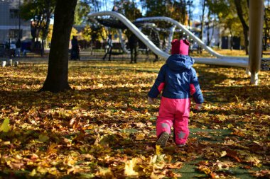 Parlak sonbahar kıyafetli küçük bir kız altın yapraklarla kaplı bir ormana doğru yürür. Sıcak mevsimlik güneş ışığında çocukluk keşiflerinin büyüsünü yakalar..