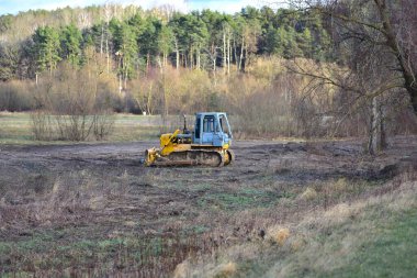 Buldozer kırsal kesimde karada, toprak hareketinde ve yer hazırlığında çalışıyor. Sanayi, kalkınma, altyapı ve arazi temizleme kavramları için uygun inşaat ve ağır makine sahnesi.