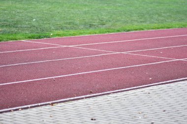 Spor stadyumunda işaretli şeritleri olan boş bir koşu pisti. Fitness, antrenman, yarışma hazırlığı ve temiz çizgiler, açık alan ve sakin atmosferli sağlıklı yaşam tarzı konsepti.