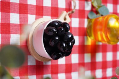 İtalyan usulü kareli masa örtüsü üzerinde siyah zeytin ve zeytin yağı.