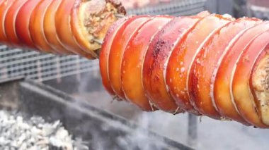 Açık ateşte dönen kızarmış domuz eti, çıtır çıtır altın kabuklu sulu et, açık hava pişirme konsepti.