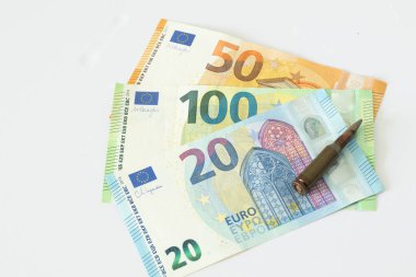 Beyaz arka planda Avro banknotları ve mermiler, silah ticareti kavramı, savaş.