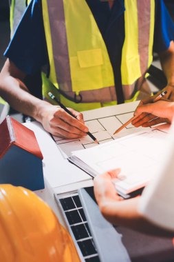 Endüstriyel mühendislerden oluşan bir ekip, fabrikadaki masada bulunan makine planlarını analiz ediyor. Fabrikada ya da üretim tesisinde çalışıyorum..