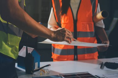 Endüstriyel mühendislerden oluşan bir ekip, fabrikadaki masada bulunan makine planlarını analiz ediyor. Fabrikada ya da üretim tesisinde çalışıyorum..