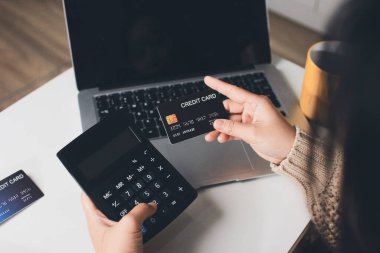 Kapanmış adam dizüstü bilgisayarı kullan kredi kartı kullan cep telefonu kullan kahve dükkanında masaya otur, dinlenme dinlenme dinlenme dinlenme dinlenme boş zamanlarında serbest mobil konsepte odaklan nesneye odaklan